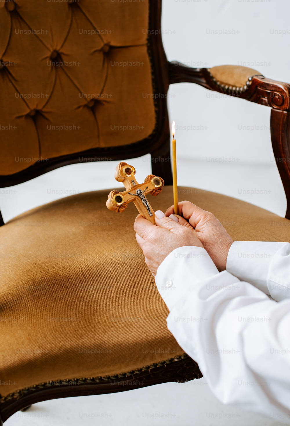 a person holding a candle and a cross on a chair