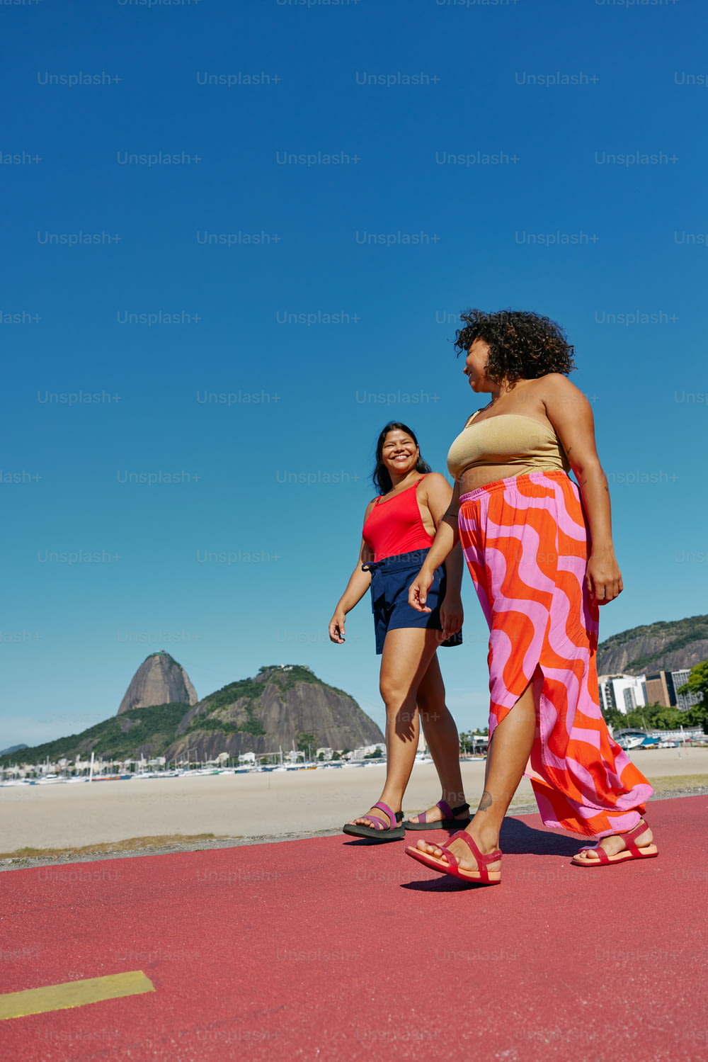 a couple of women walking across a beach