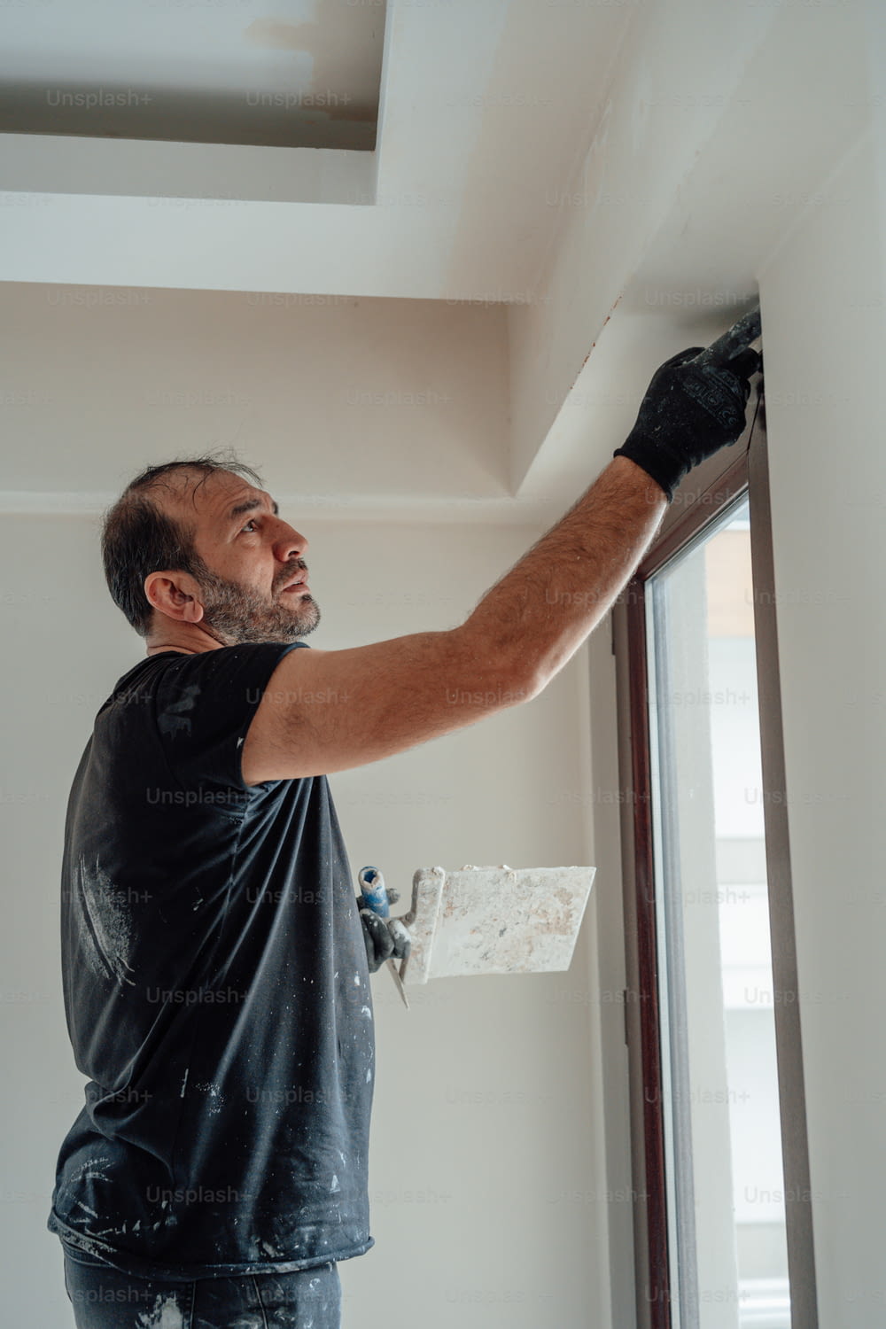 a man in black shirt and black gloves painting a wall