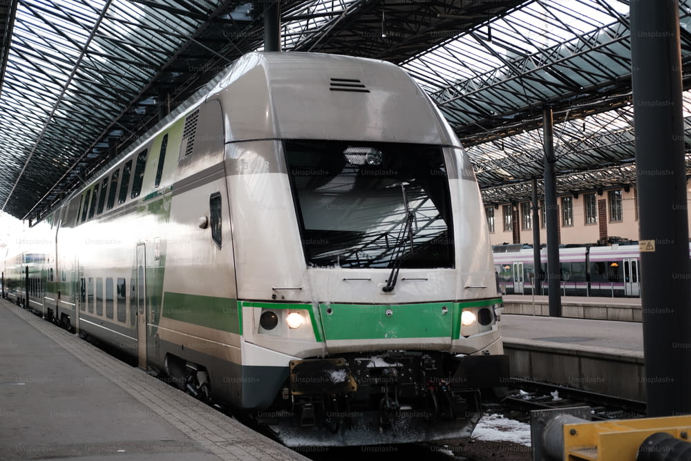 Ein weiß-grüner Zug fährt in einen Bahnhof ein