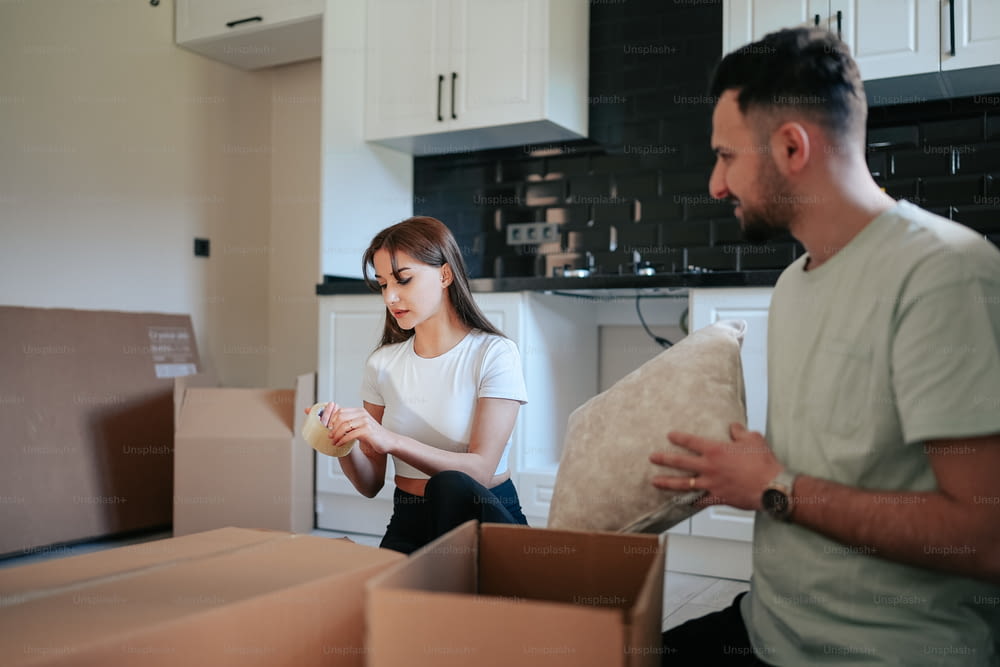 a man and a woman unpack boxes in a kitchen
