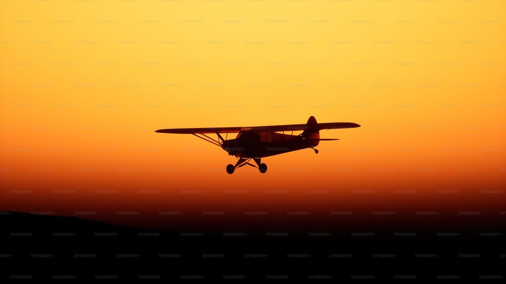 um pequeno avião voando no ar ao pôr do sol