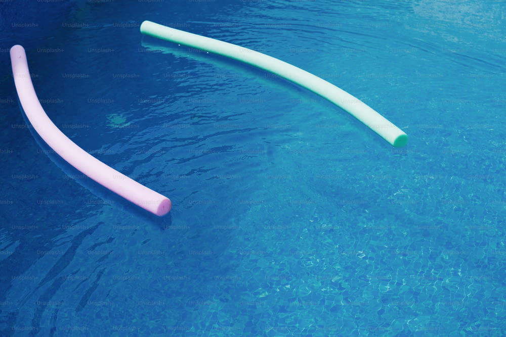 um par de tubos rosa e branco flutuando em uma piscina