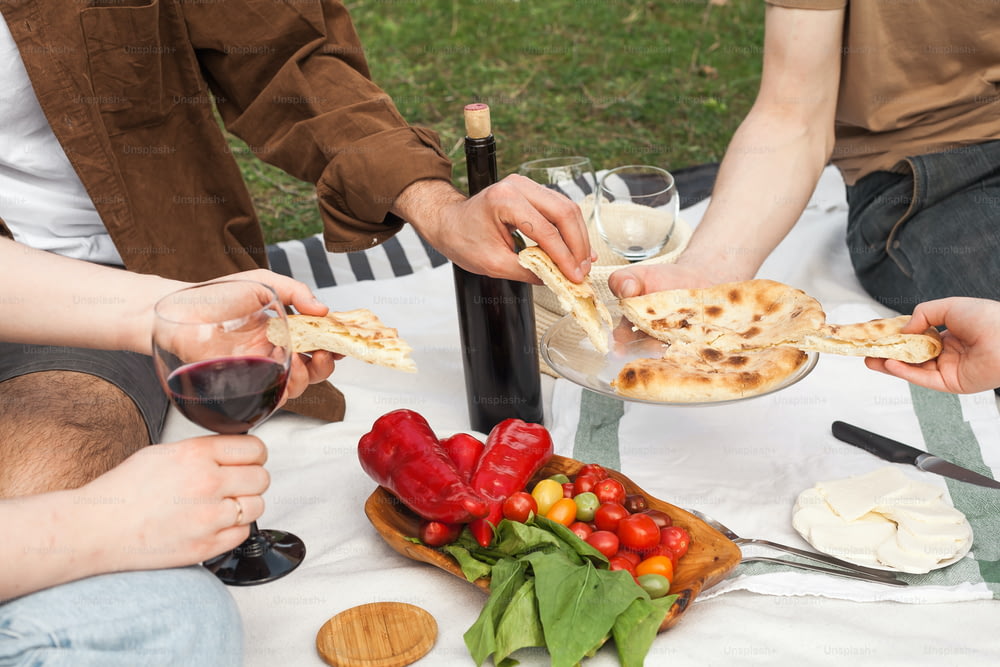a group of people sitting around a table with food and wine
