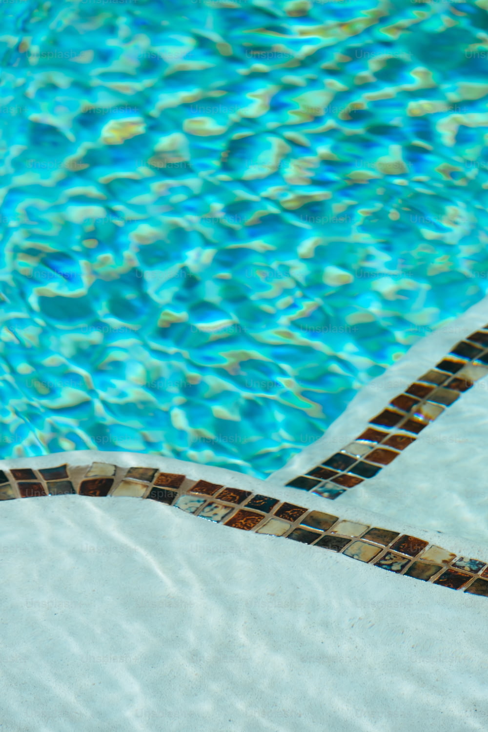 une piscine avec une bordure carrelée et de l’eau bleue