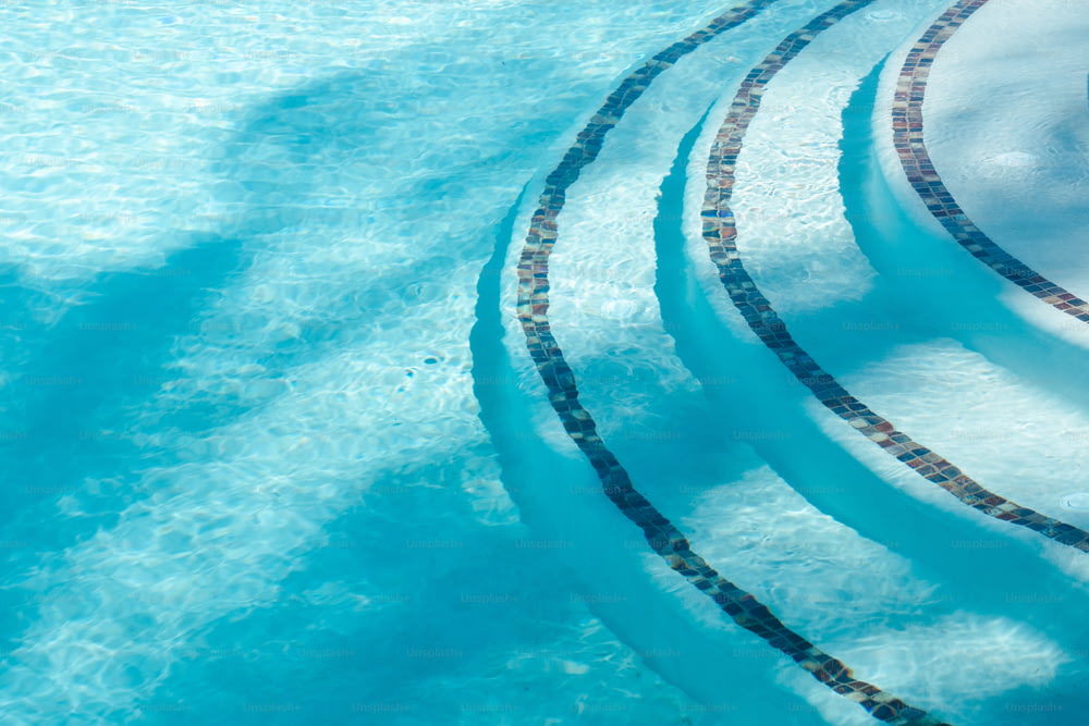 une piscine avec un bord carrelé et de l’eau bleue