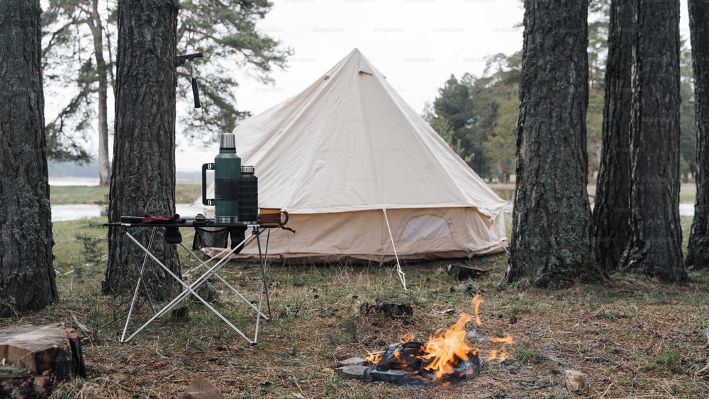 a tent is set up next to a campfire