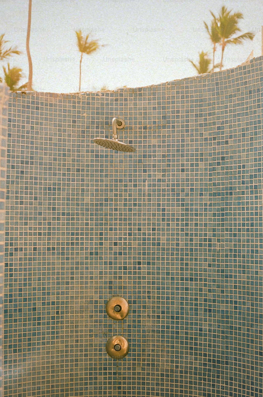 a tiled shower with a shower head and hand held shower faucet