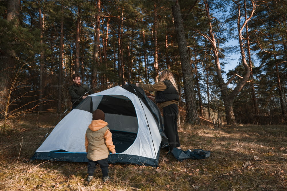 Ein Mann und ein Kind bauen ein Zelt im Wald auf