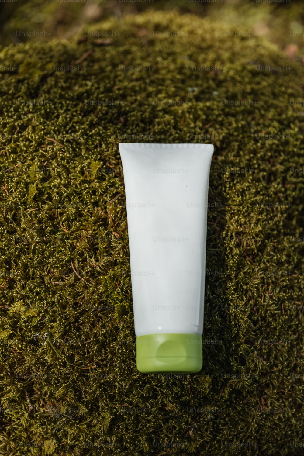 a tube of cream sitting on top of a moss covered ground