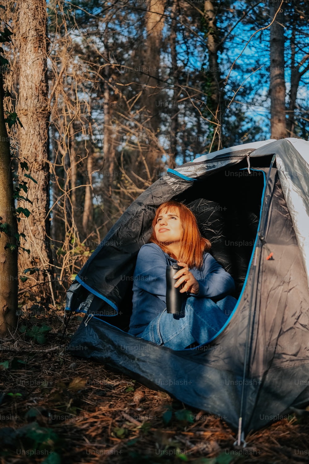Eine Frau sitzt in einem Zelt im Wald
