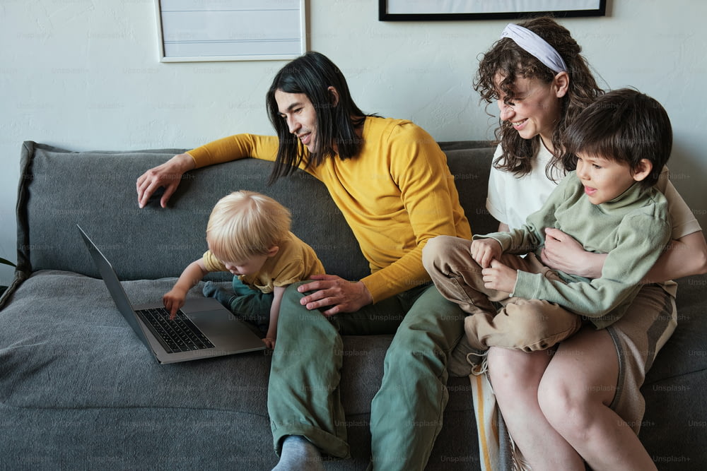 a woman sitting on a couch with two children and a laptop