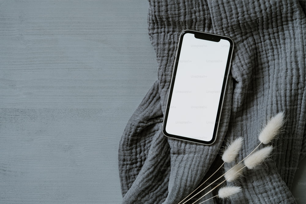 Un telefono cellulare seduto sopra una coperta grigia