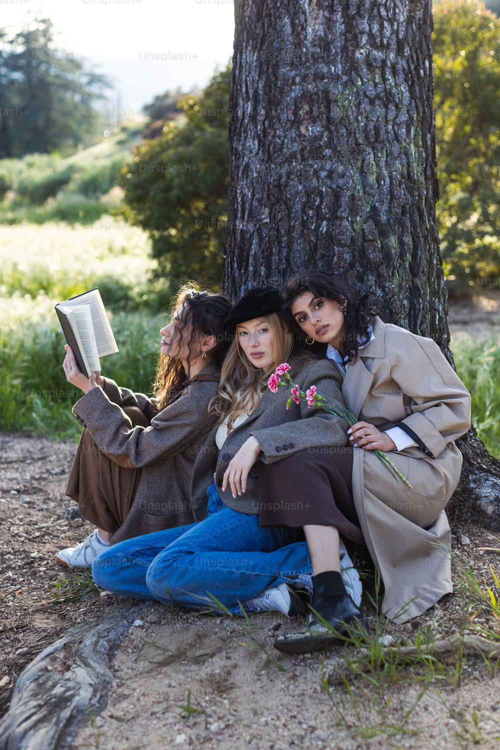 木の下に座って本を読む2人の女性