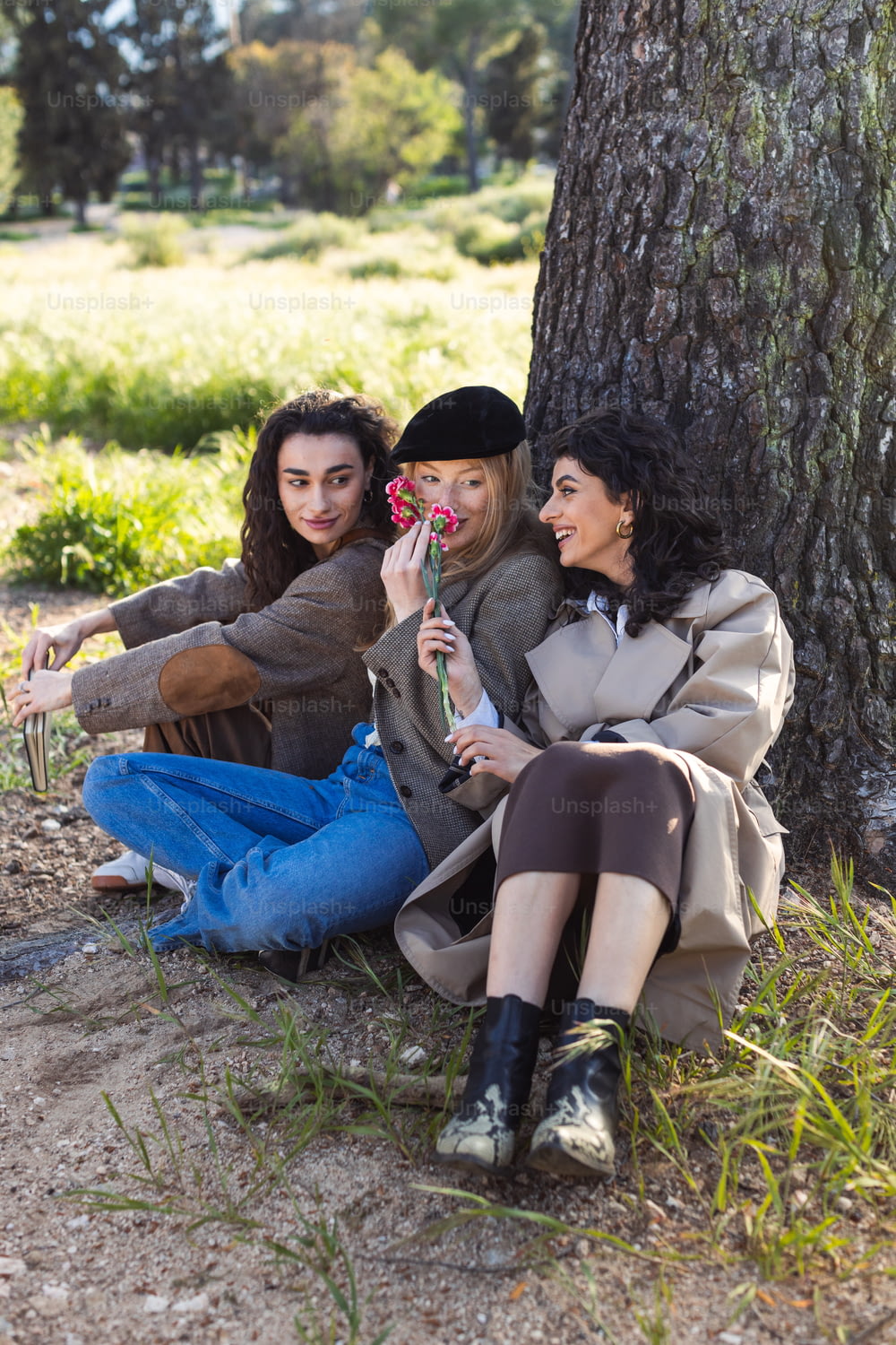 Tre donne sedute a terra accanto a un albero