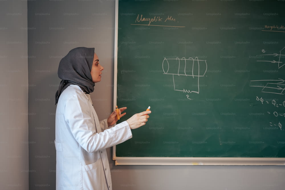 Une femme en hijab écrivant sur un tableau noir