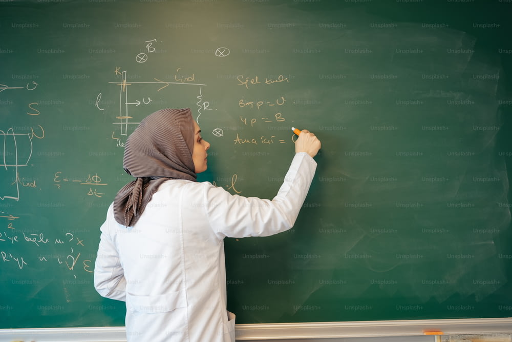 a woman writing on a blackboard with a marker