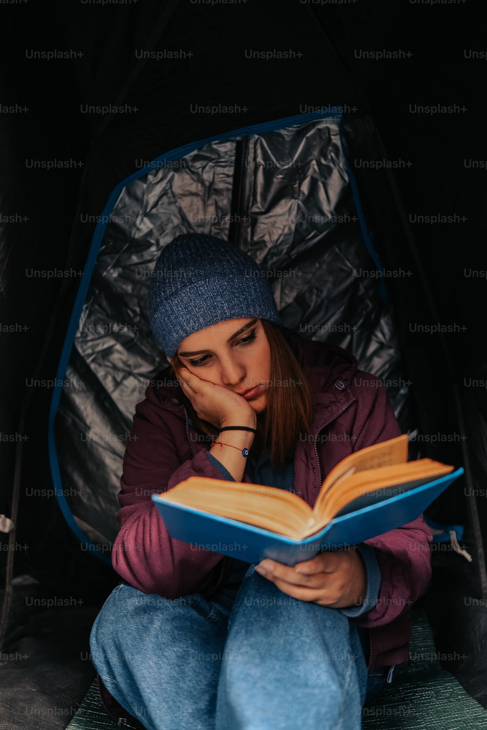 una donna seduta in una tenda che legge un libro