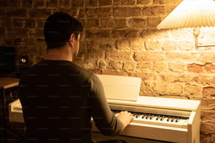 Un homme assis à un piano devant une lampe