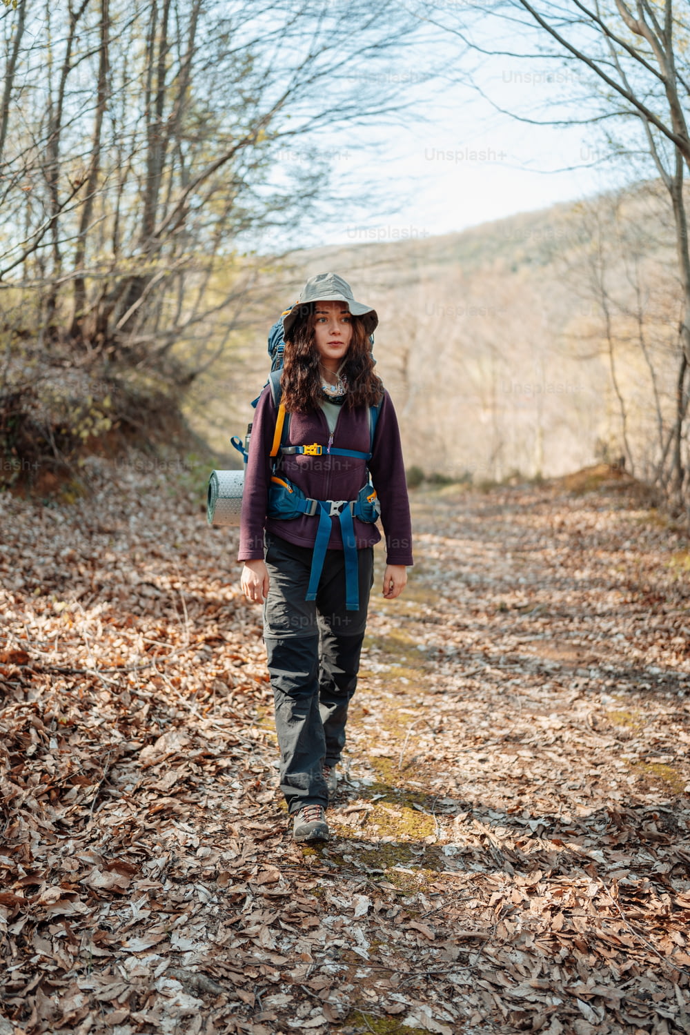 a woman with a backpack is walking in the woods