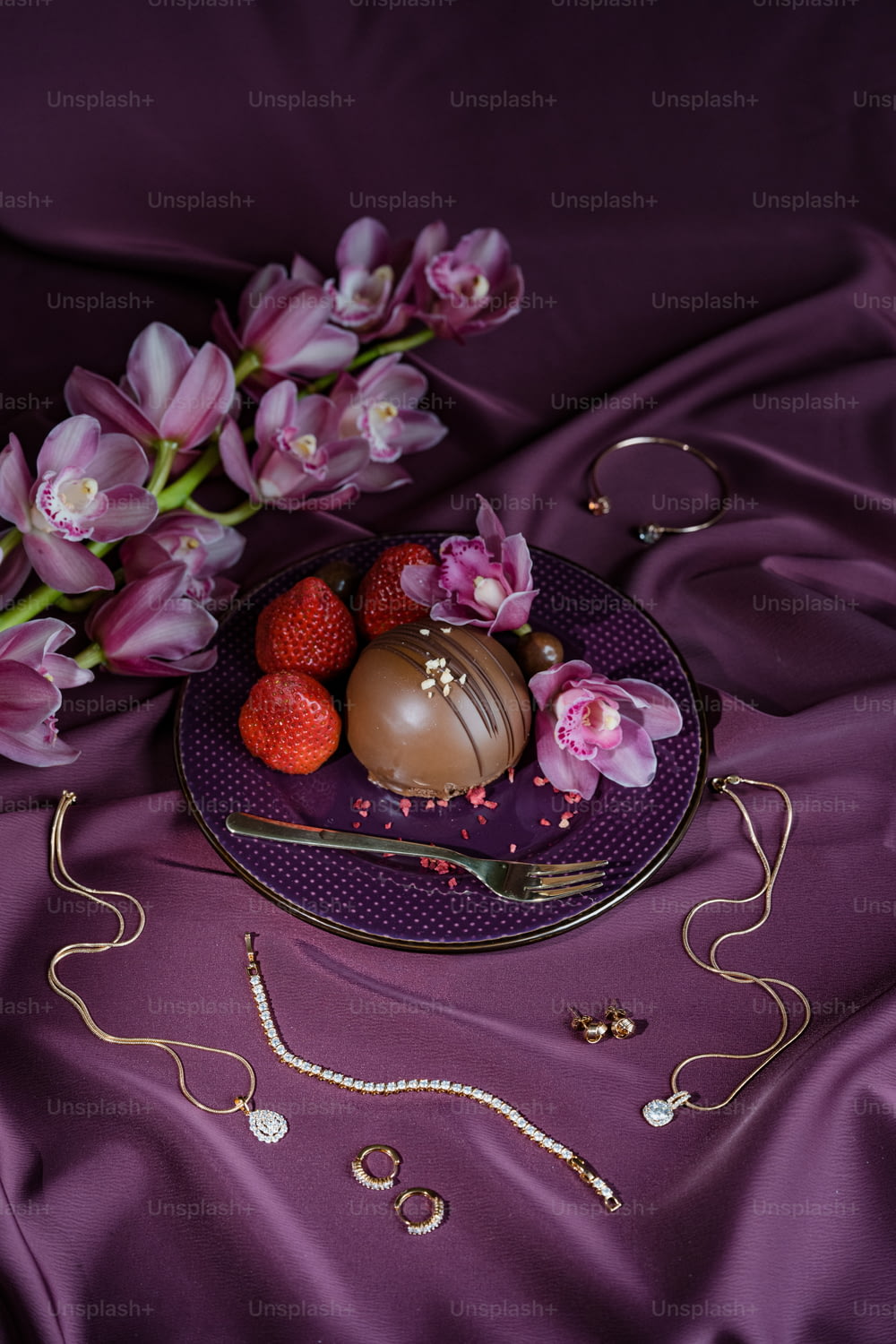 a plate of chocolates and flowers on a purple cloth