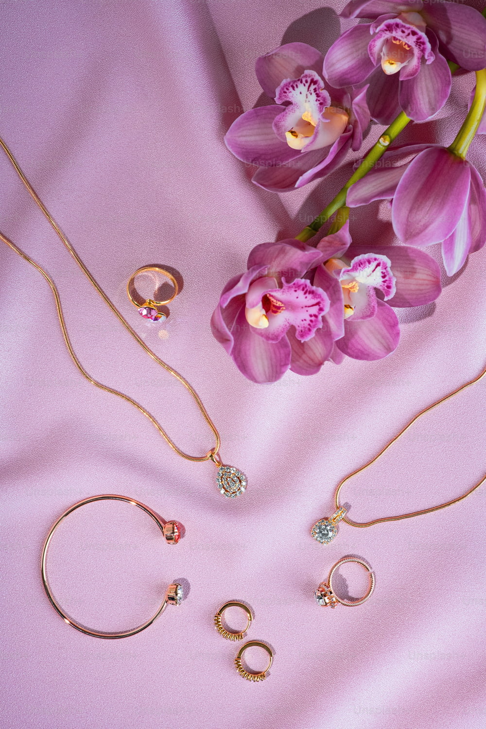 a bunch of jewelry laying on a pink surface