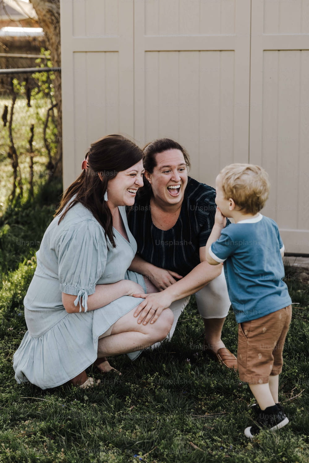 um homem, uma mulher e uma criança rindo juntos na grama