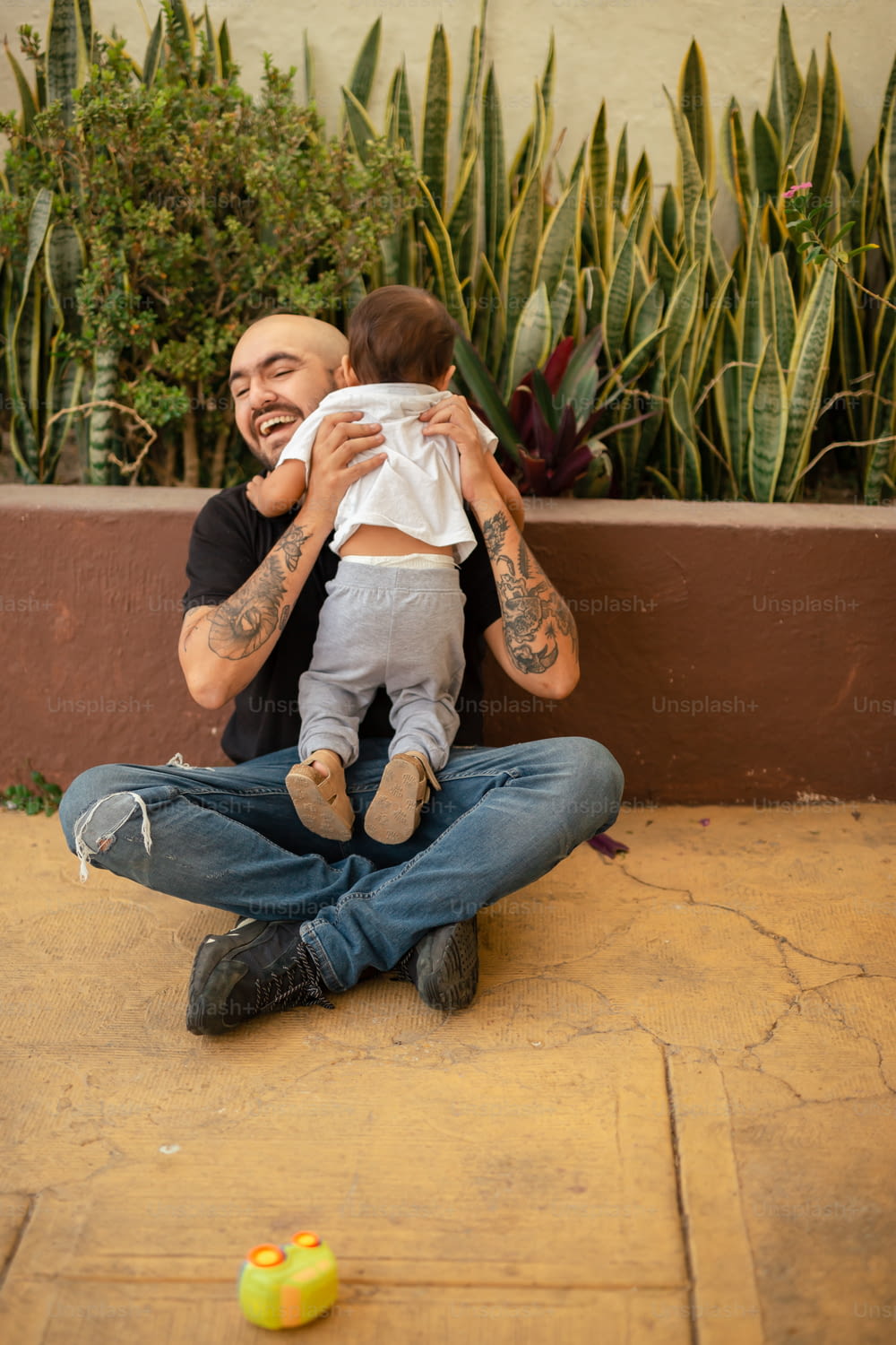 a man sitting on the ground holding a baby