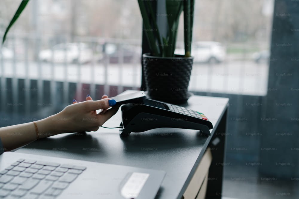 Una persona che utilizza un telefono su una scrivania accanto a un laptop