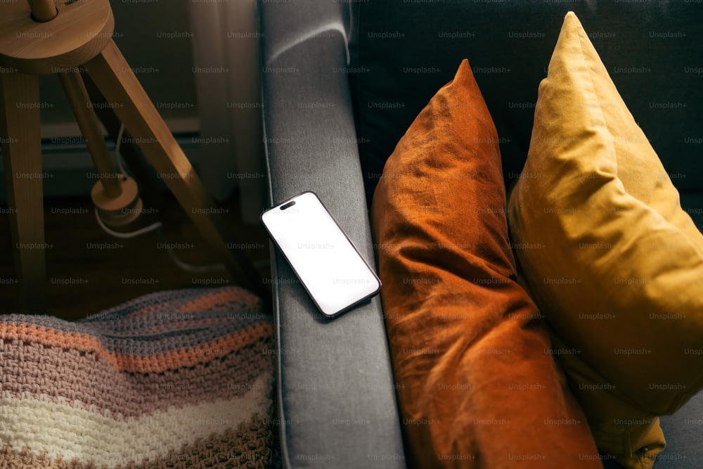 a cell phone sitting on top of a couch next to pillows