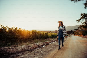Caucasian female farmer walking through vineyards at sunrise holding basket of fresh vegetables loving work. High quality photo