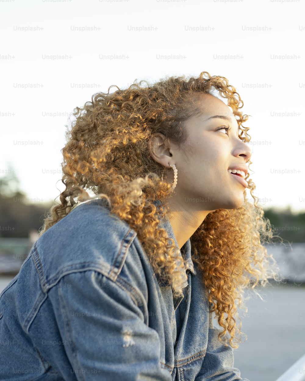 mulher bonita com cabelo encaracolado, foto de perfil ao ar livre, pensando, observando