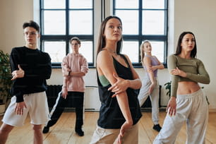 流行のダンスの新しい動きを学びながら、ダンスインストラクターの後に繰り返すズボンとタンクトップの現代の10代のグループ
