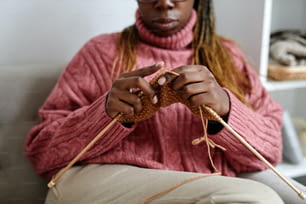 家で居心地の良い週末を楽しみながら編み物をしている若いアフリカ系アメリカ人女性のトリミング、コピー用スペース