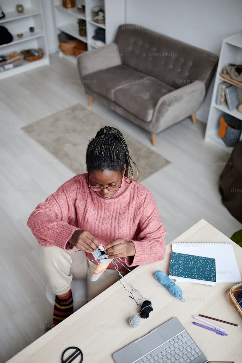 Hochwinkelporträt einer jungen afroamerikanischen Frau, die zu Hause in einem gemütlichen Raum strickt, Kopierraum