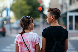 Madre e hija esperando luz verde para cruzar la calle mientras se miran