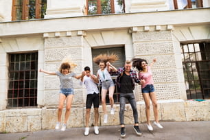Agrupe estudantes adolescentes atraentes em frente à universidade pulando alto.