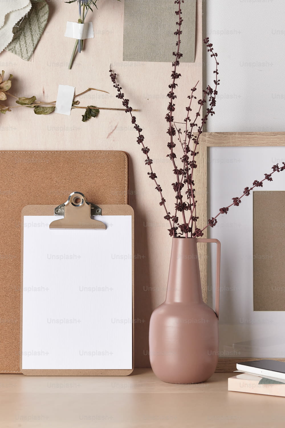 a pink vase with flowers in it next to a clipboard