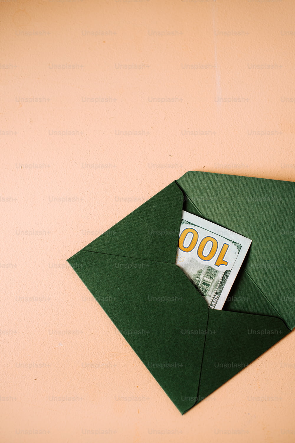 a green envelope with a hundred dollar bill sticking out of it
