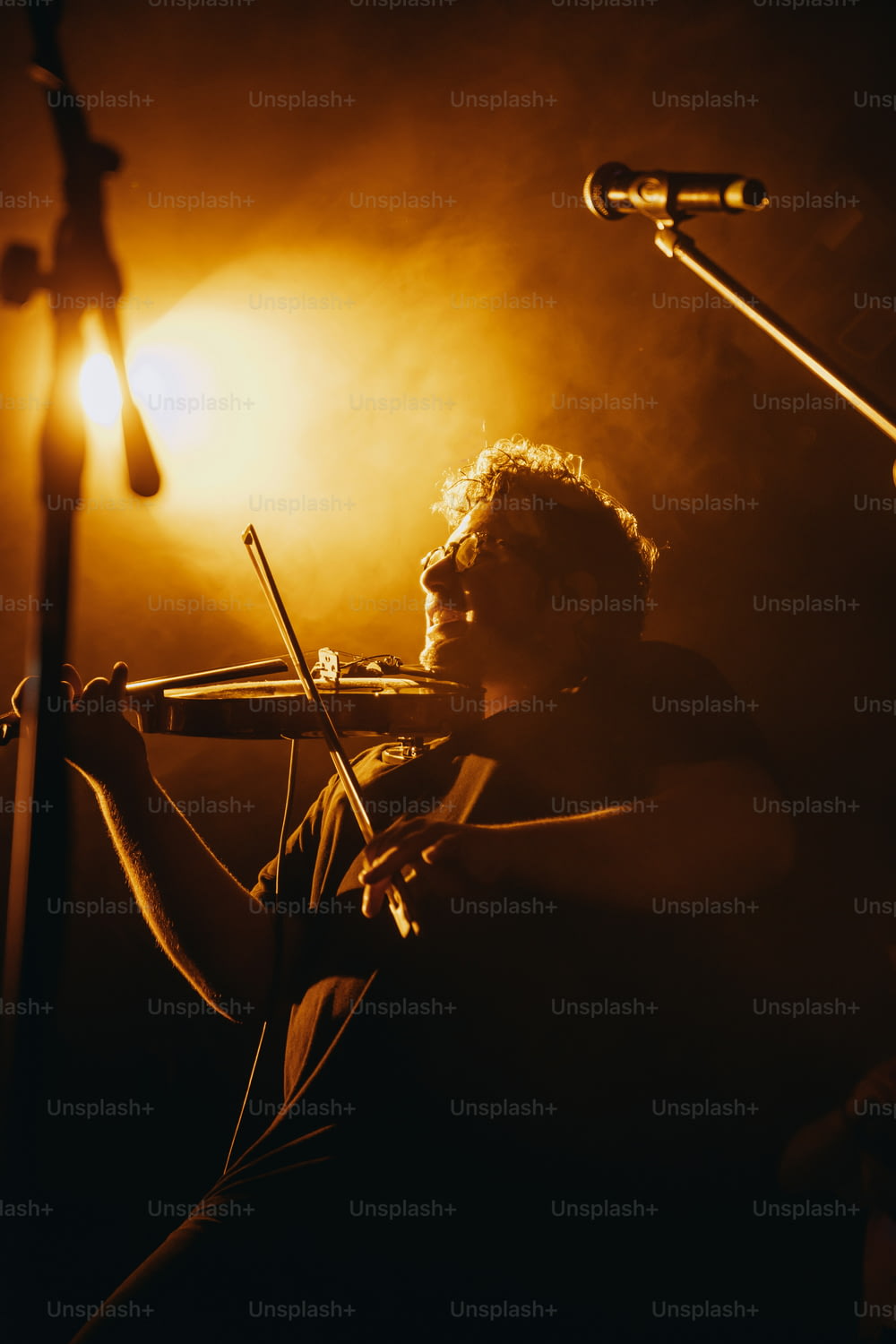 a man playing a violin in front of a microphone