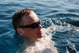 Un homme nageant dans l’océan portant des lunettes de soleil