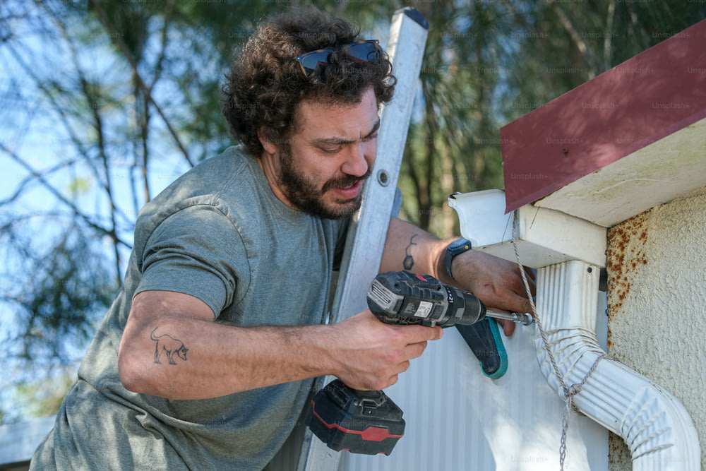 a man using a drill to fix a gutter gutter