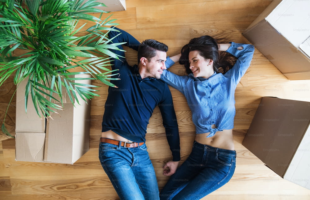 A top view of young couple with cardboard boxes lying on the floor, moving in a new home.