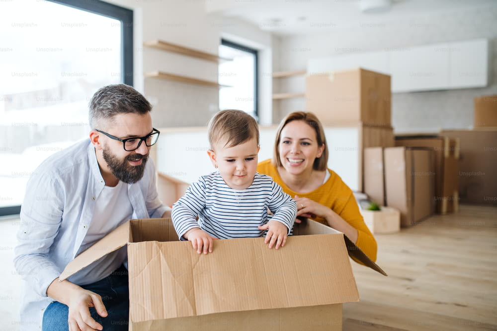 A portrait of happy young family with a toddler girl moving in new home.