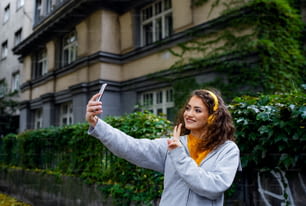 Portrait of young woman with smartphone outdoors on street, video for social media concept.