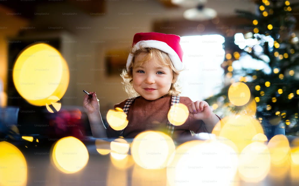 Porträt eines glücklichen kleinen Mädchens, das zu Weihnachten zu Hause ist und Bilder malt.