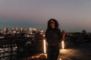 A young woman with sparklers having fun at rooftop in the city, close up.