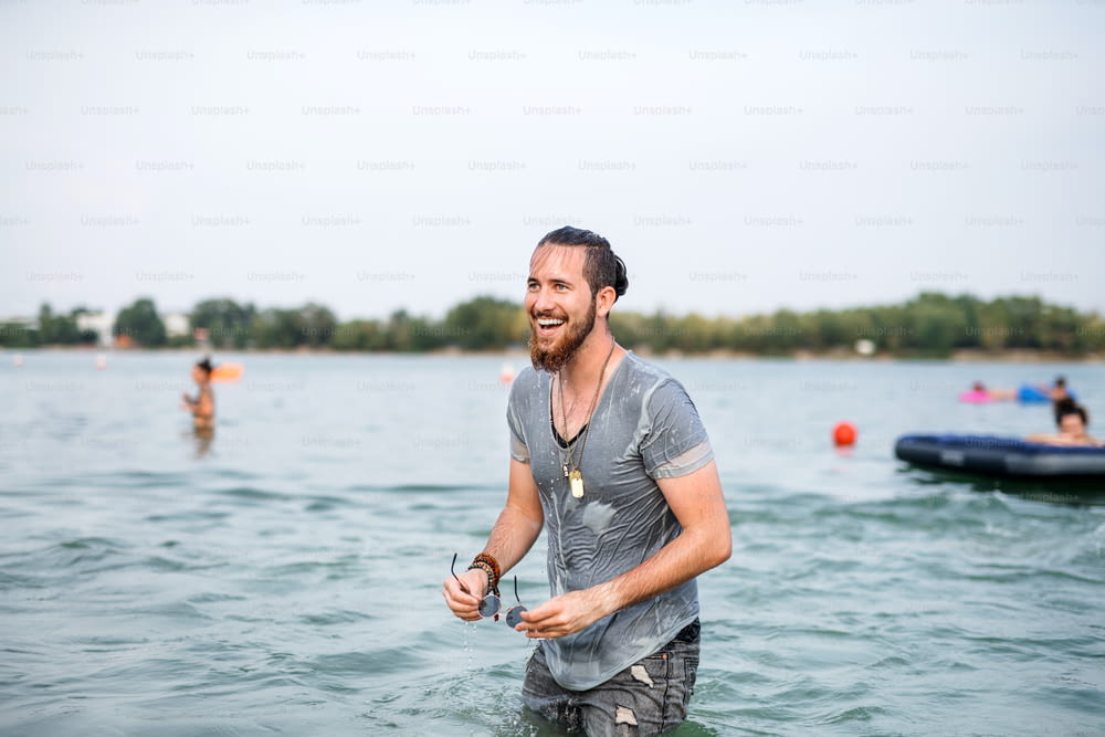Jeune homme mouillé s’amusant au festival d’été, debout dans le lac. Espace de copie.