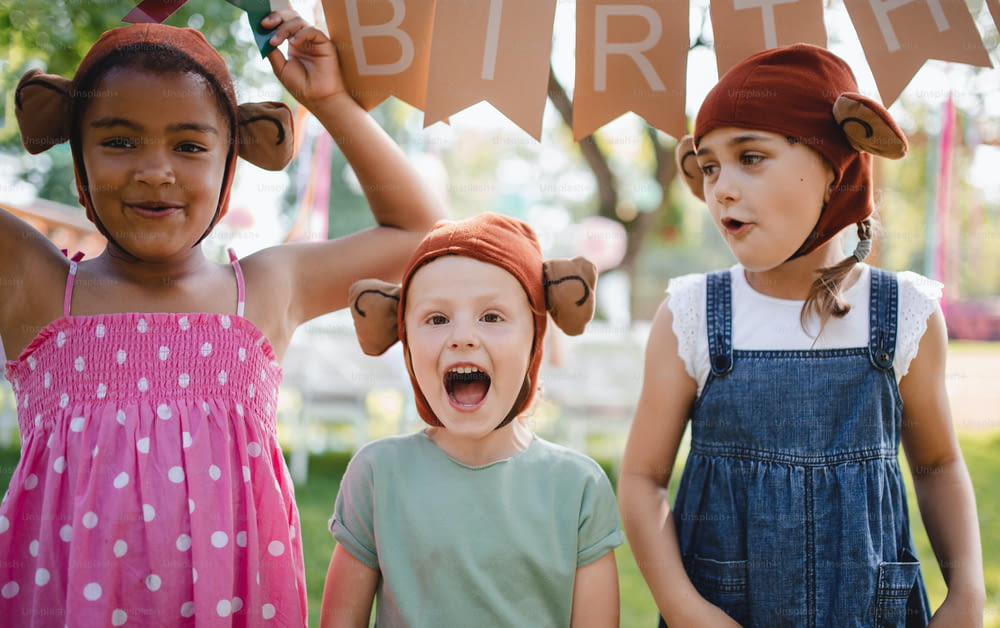 Niños pequeños con máscaras de pie al aire libre en el jardín en verano, jugando. Un concepto de celebración.