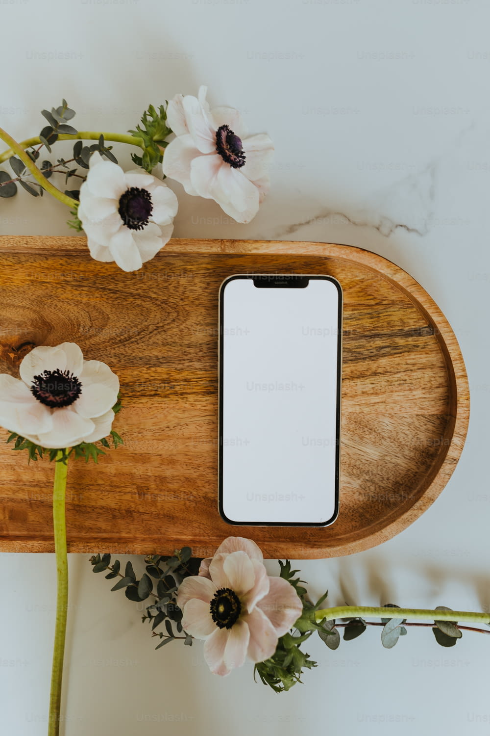 un vassoio di legno con fiori e un telefono cellulare su di esso